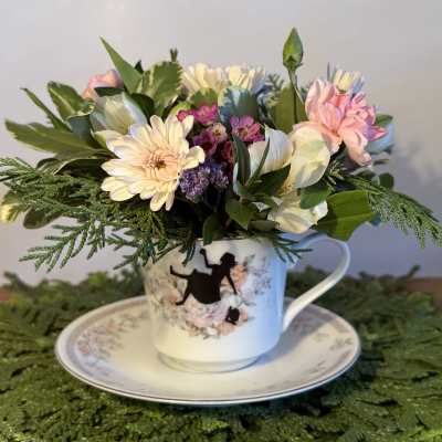 Pastel flower arrangement in a teacup on a saucer