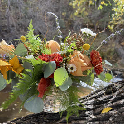 Mixed bouquet in a woven vase with peach, red, and white flowers