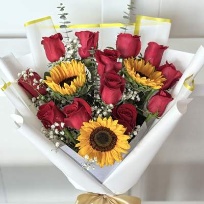 Bouquet of red roses and sunflowers wrapped in white paper
