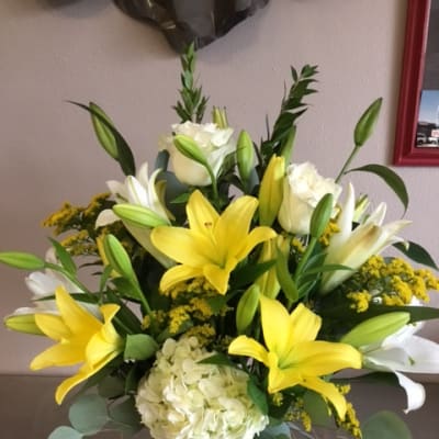 Yellow lilies and white roses in a vase with pale hydrangea