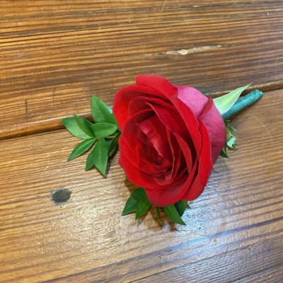 Single red rose boutonniere with wrapped stem on a wooden surface