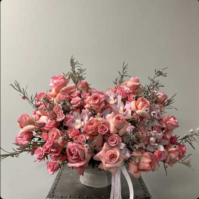 Large pink rose arrangement in a clear vase with ribbon