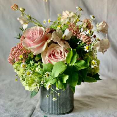 Pink roses and small white daisies arranged in a metal vase.