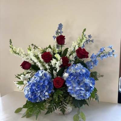 Blue hydrangeas and red roses in a white basket arrangement