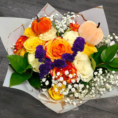 Bouquet of yellow, orange, and white roses with small white filler flowers and plush pumpkins