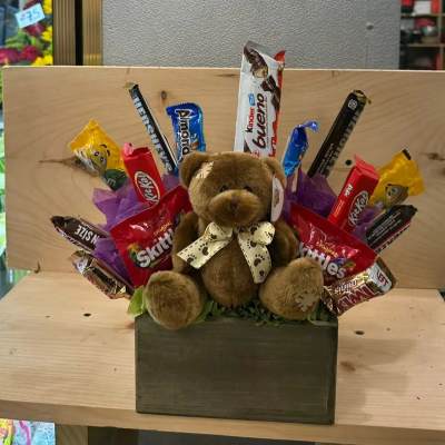 Gift box with plush teddy bear surrounded by assorted candy bars and sweets