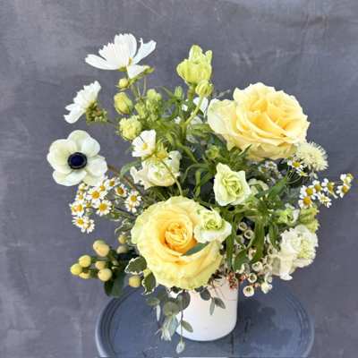 Yellow roses and white flowers arranged in a white vase