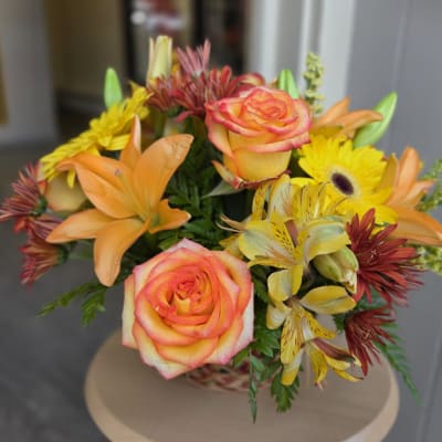 Bouquet of orange-pink roses and yellow flowers in a basket