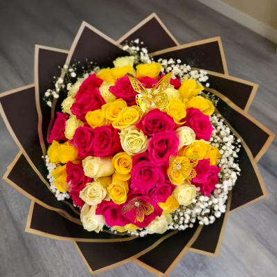 Bouquet of pink, yellow, and cream roses with butterfly picks