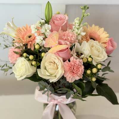 Pink and white flower bouquet in a glass vase with a ribbon