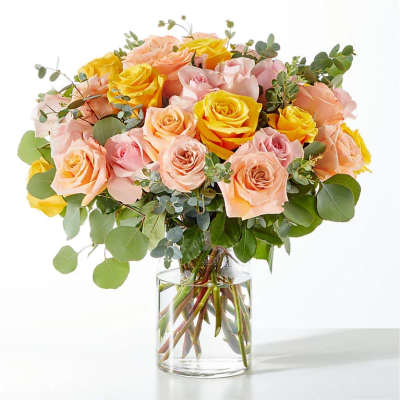 Bouquet of pink and yellow roses in a clear glass vase