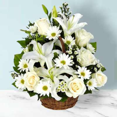 White lilies, roses, and daisies arranged in a wicker basket