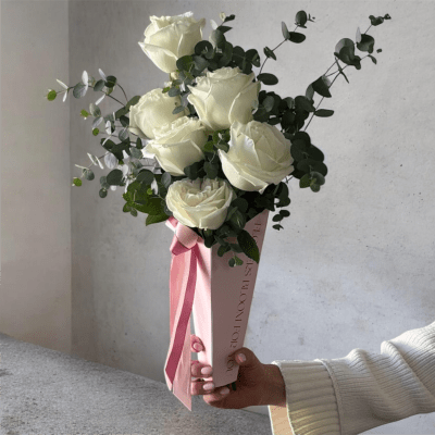 Bouquet of white roses with eucalyptus in a pink wrap and ribbon