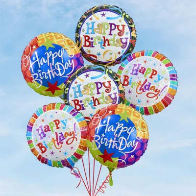 Cluster of colorful Happy Birthday balloons against a blue sky