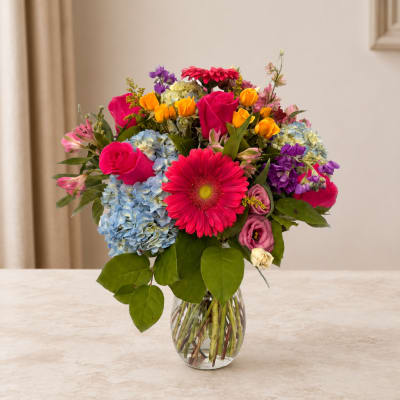 Mixed bouquet of bright flowers in a clear glass vase