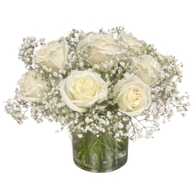White roses and baby's breath arranged in a clear glass vase