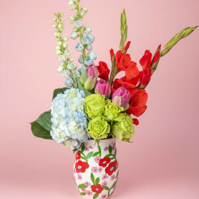 Colorful bouquet in a painted vase with hydrangeas, tulips, and red gladiolus