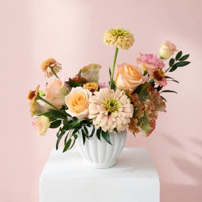 Peach and pink flower arrangement in a white vase