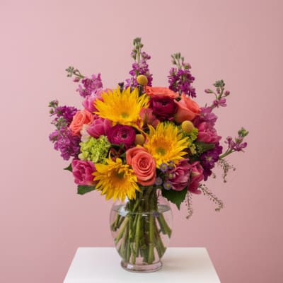 Colorful mixed bouquet in a clear glass vase on a white table