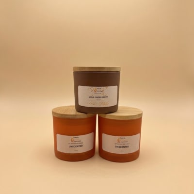 Three labeled candles with wooden lids on a neutral background