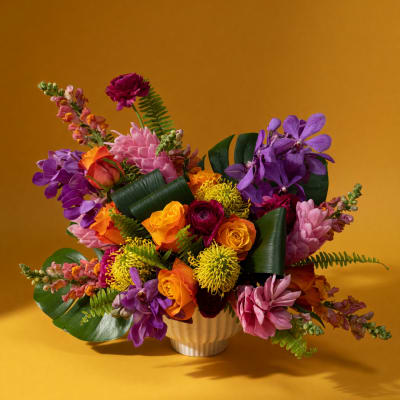 Colorful bouquet of roses, orchids, and mums in a white vase
