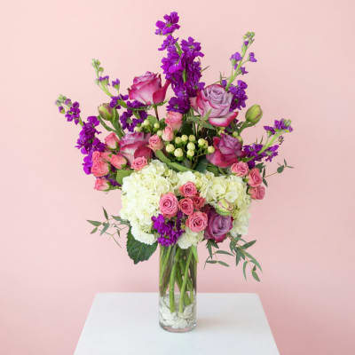 Pink and purple mixed flower arrangement in a clear glass vase