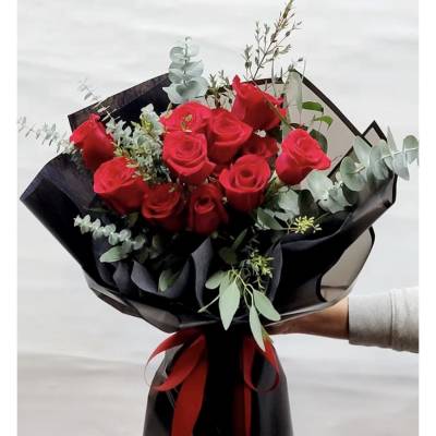 Bouquet of red roses wrapped in black paper with a red ribbon