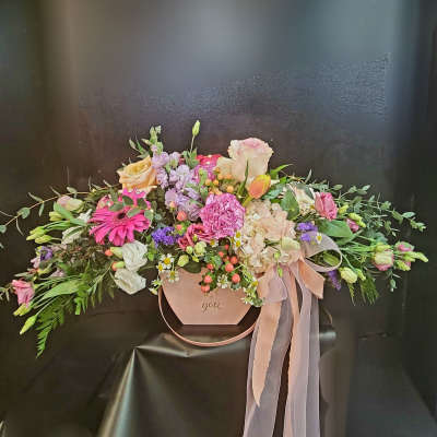 Pastel floral arrangement in a pink hat box with ribbon
