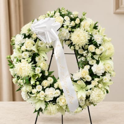White floral wreath with a satin bow on a stand