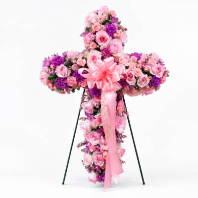 Pink and purple floral cross on a stand with a pink ribbon