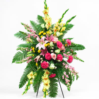 Standing floral spray with pink, yellow, and white flowers on a tripod easel