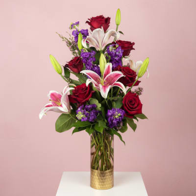 Red roses and pink lilies arranged in a tall glass vase