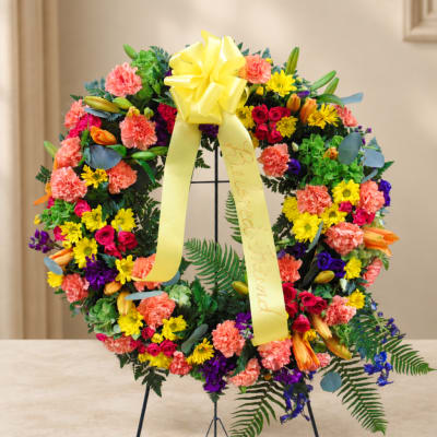 Colorful floral wreath on a stand with a yellow ribbon bow