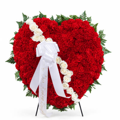 Heart-shaped red floral wreath with white roses and a white ribbon