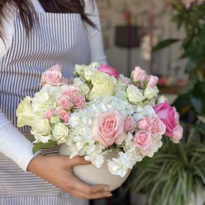 Pink and white roses arranged in a white bowl vase