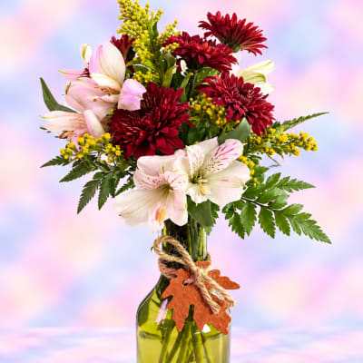 Bouquet of red chrysanthemums and pale pink lilies in a glass vase