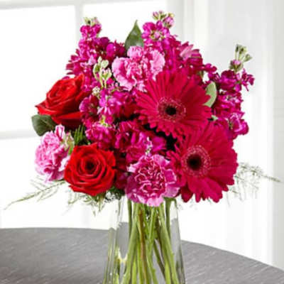 Bouquet of red roses and pink flowers in a clear glass vase