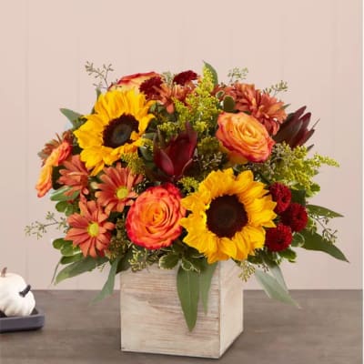 Mixed bouquet with sunflowers, roses, and mums in a wooden cube vase