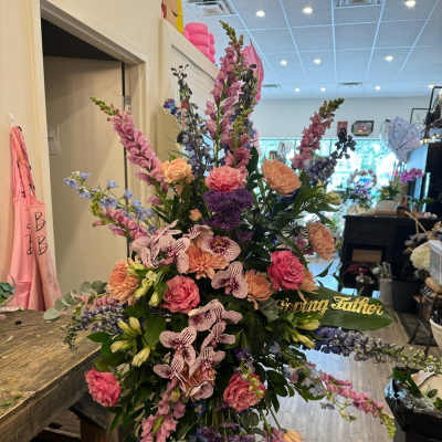 Tall floral standing spray with pink, purple, and peach blooms