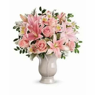 Pink lilies and roses arranged in a white vase