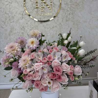 Large pink floral arrangement in a white vase with roses and tulips