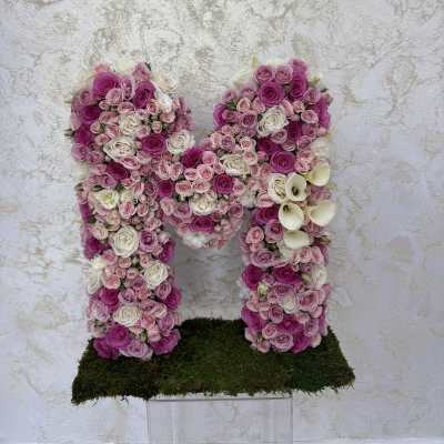 Pink and white rose arrangement shaped like the letter M