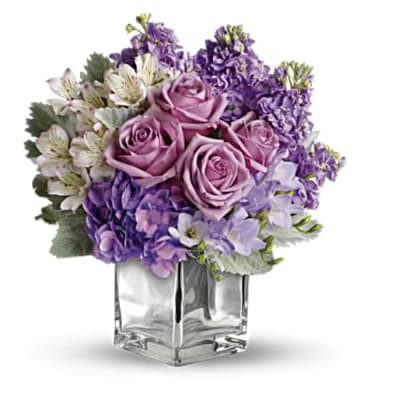 Lavender roses and purple flowers in a clear square vase