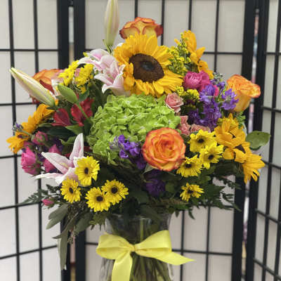 Mixed bouquet in a glass vase with a yellow ribbon