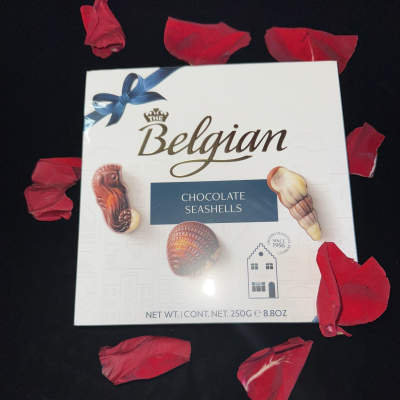 Box of Belgian chocolate seashells surrounded by red petals