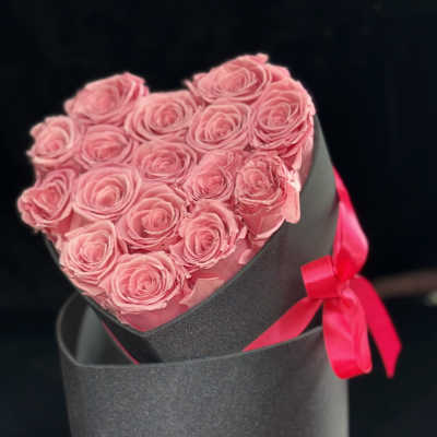 Pink roses arranged in a black hatbox with a bright pink ribbon