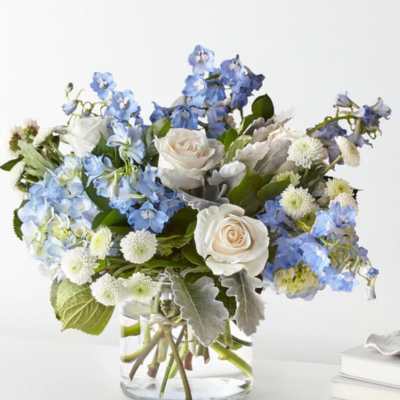 Blue and white bouquet of roses and mixed blooms in a glass vase