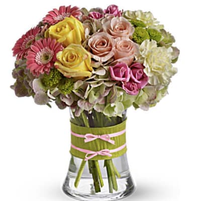 Mixed bouquet of roses, gerbera daisies, and hydrangeas in a glass vase