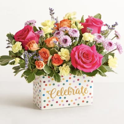 Mixed bouquet of pink, orange, and yellow flowers in a polka-dot box
