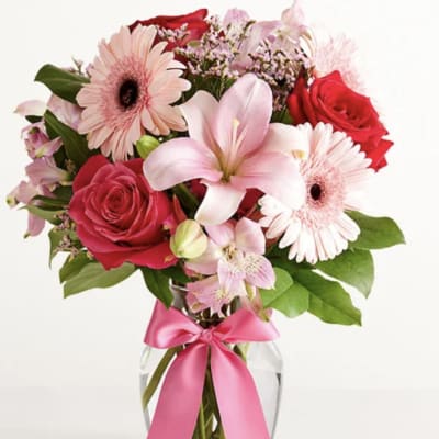 Pink and red mixed bouquet in a glass vase with a pink ribbon